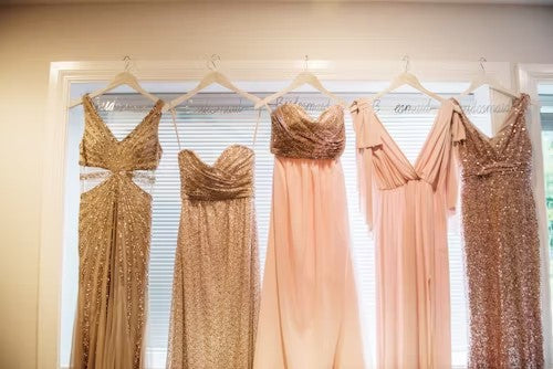 Rosy pink bridesmaid dresses hanging on display in a boutique, evoking soft summer wedding tones and inspiration for Ms. Jetsetter’s Rosegold Travel Trio.